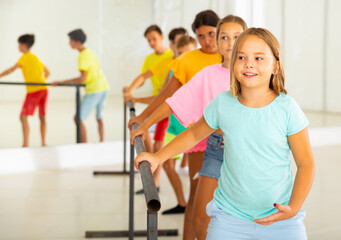 Group of smiling children practicing at the ballet barre