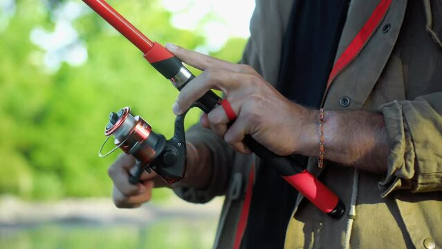 Fishing in nature with a man in a tourist robe. Men's hands hold a fishing rod.