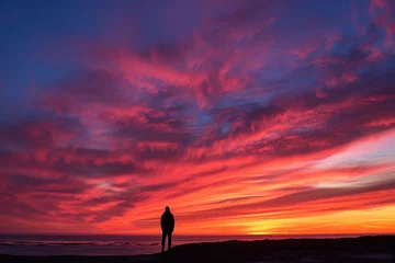Gordijnen A lone figure silhouetted against a vibrant sunset © Daniel