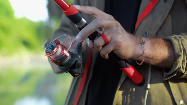 Fishing in nature with a man in a tourist robe. Men's hands hold a fishing rod.