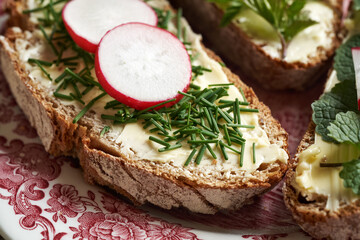 Spring wild edible plants - onion grass, garlic mustard and ground elder, on slices of sourdough bread, closeup
