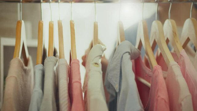 Clothes hangers. Fashionable woman dressed in a bright shirt looking through clothes on hangers in an exclusive boutique. Model woman chooses clothes follows fashion trends and trends, texture