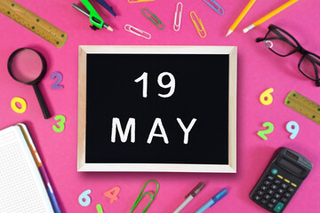 May 19 written in chalk on black board. Calendar date 19th of May on chalkboard on pink blurred...