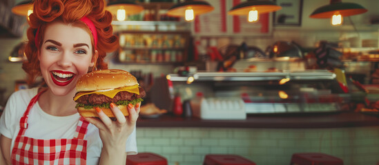 Beautiful waitress with red hair hold big burger posing and smiling in a restaurant against the background of the counter.
