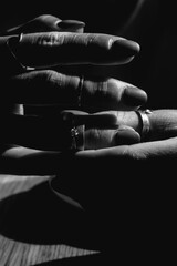 Black and white close-up of women's fingers with stylish silver and white gold jewelry. Concept of...