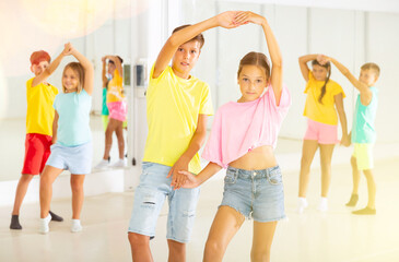 Fototapeta premium Portrait of positive tweenagers practicing slow ballroom dances in pairs in choreographic studio.