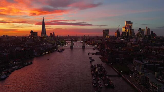 Establishing aerial view of the London skyline with Tower Bridge and City skyscrapers during a colorful sunset