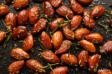 Roasted rosemary almonds  on a black background, close up view