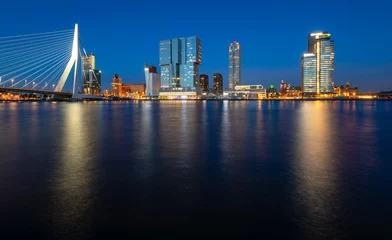 Foto auf Alu-Dibond Panoramic view of Rotterdam night time skyline with modern buildings and iconic bridge. Evening sky reflection in River Maas at blue hour with colorful illumination. Major port and big dutch metropole © ON-Photography
