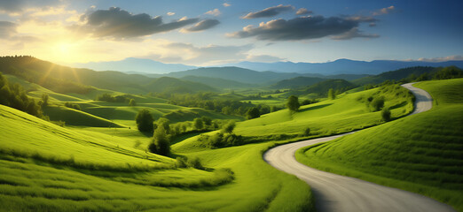 A winding road runs through a lush green field. The sky is clear and the sun is shining