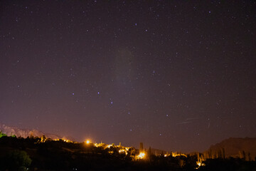 time lapse of clouds over city. a city is shown in the night sky with a star - filled sky.