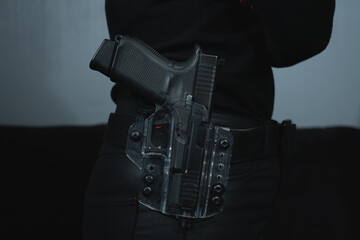 The girl has a pistol in a transparent holster on a belt on her belt, close-up photo.