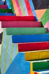 A view of a staircase with steps painted in bold colors and geometric patterns adding a playful...