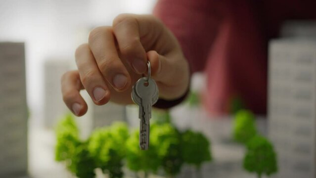 The keys to a new house lie in the hand of a man ready to move. A young guy receives the keys to his first home. The purchase of an apartment is completed, the keys are in hand. New life