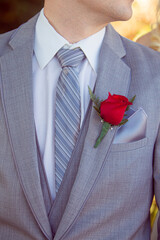 Closeup red rose boutonniere on groom