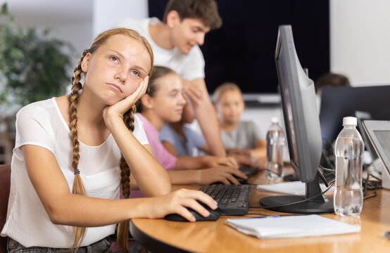 Portrait of disgruntled teenage girl at a computer in a school computer class