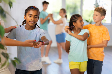 Active preteen children practicing Ballroom dances in pairs in training hall during dancing classes