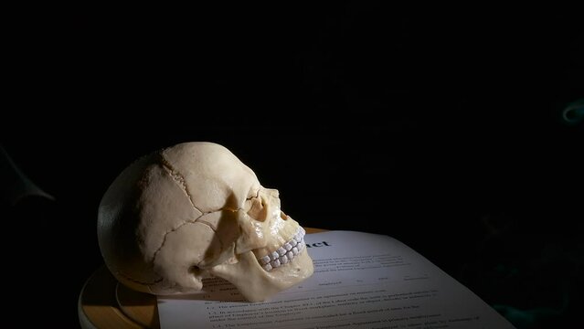 Troubled personal contract. A view of troubled personal contract lay on the table with human skull against black background.