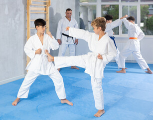 Diligent preteen karate students practicing fighting techniques during workout session