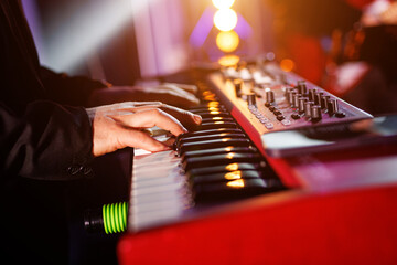 Musician hands on the modern piano keyboard keys, side view.