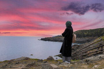 Lonely and sad girl watching sunset by the sea. Longing for the distance and the past.