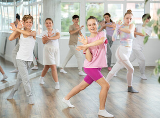 Obraz premium Team of positive teenagers rehearsing modern dances in dance hall