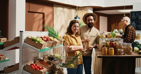 Zoom out shot of happy green living couple buying pantry staples from zero waste supermarket....