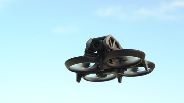drone with protections on propellers flying with blue sky, detailed view of the front camera, horizontal video