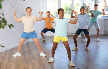 Fototapeta premium Group of positive juvenile boys and girls engaged in sport dances in training room during workout session