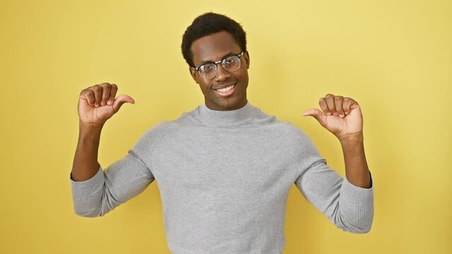 Young african american man wearing glasses standing looking confident with smile on face, pointing oneself with fingers proud and happy. over isolated yellow background