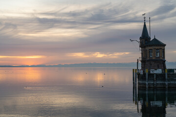 Der Leuchtturm an der Hafeneinfahrt mit dem ruhigen See und den Bergen am Horizont in der...