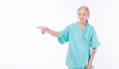 Healthy cheerful grandmother patient gown pointing finger copy space standing over isolated white...