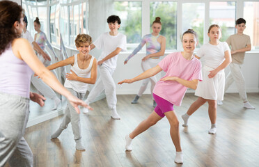 Girl teen performs modern dances repeats movements of unrecognizable teacher together with friends...