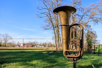 A large brass instrument is sitting in a grassy field