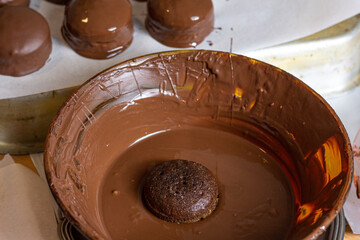 Bolo saboroso e fresco mergulhado no chocolate quente derretido pronto para ser banhado