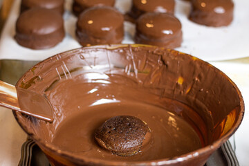 Bolo fresquinho mergulhado no chocolate derretido pronto para ser banhado