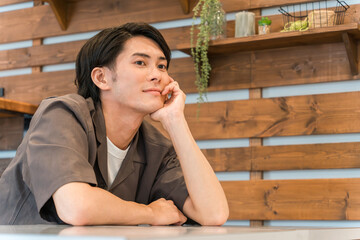 家・カフェでくつろぐ笑顔の若いアジア人・日本人男性（リラックス）
