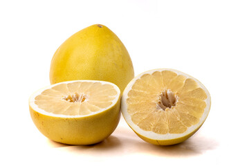 A whole pomelo grapefruit with one cut in half showing the inside segments isolated on white