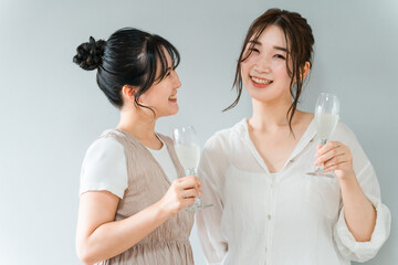 女子会・ホームパーティーでシャンパングラスを手に談笑する女性（ママ友・友人・親友）  © buritora