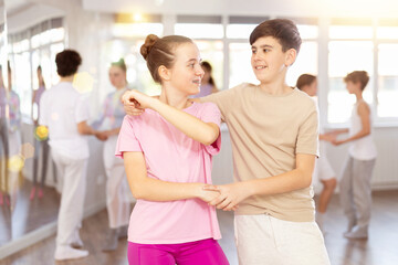 Teen girl paired with guy practices movements of rumba dance and trains to perform movements during...