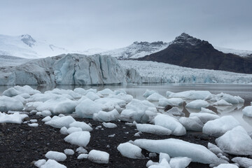 Ice chunks scattered  at the shore of Fjallsarlon glacier lagoon on a  overcast day in Vatnajokull...