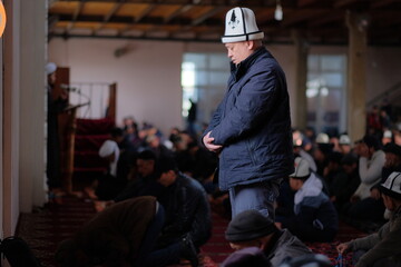 A Kyrgyz man in Kyrgyz national headwear is praying in the mosque.