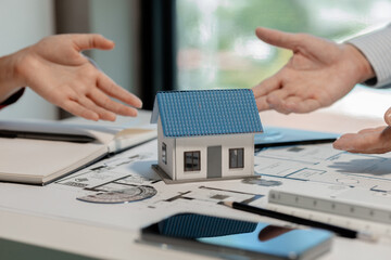 Fototapeta premium An engineer is working with a colleague in an office is discussing a model of a house designed as a prototype for a client and is reaching agreement that the design is what the client wants.
