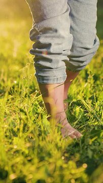 Boy go barefoot on green grass in park. Children feet walk on green grass in summer, slow motion. Little bare legged kid girl, Healthy baby go in nature, active game. Happy family, children happiness