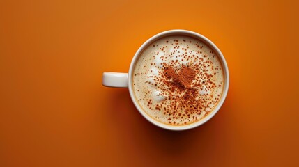 Warm pumpkin spice latte in white cup on orange background