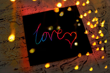 Note I love you for Valentines Day. Art scratch paper for message. String lights, shiny