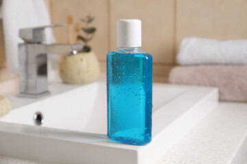 Fresh mouthwash in bottle on sink in bathroom, closeup
