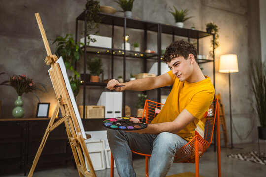 young man caucasian male student paint painting at home hold brush