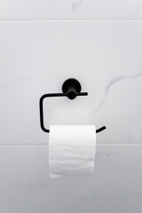 black toilet paper roll holder on white marble tiled wall, home renovation and detail in powder...