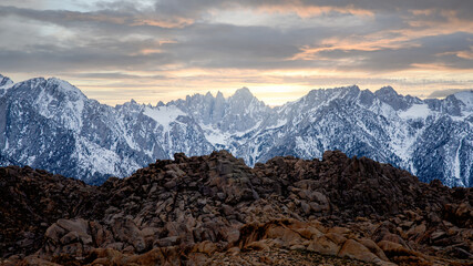 Sunset moment on the mountains with snow and rocks on the foreground